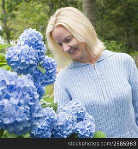 Mid adult woman looking at flowers in a lawn and smiling