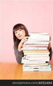 Mid adult woman looking at stack of books on desk