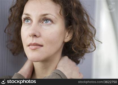 Mid adult woman looking up with hands holding neck
