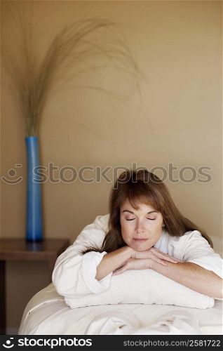 Mid adult woman lying on a massage table with her eyes closed