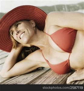 Mid adult woman lying on a pier and smiling