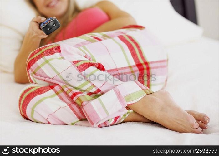 Mid adult woman lying on the bed and watching television