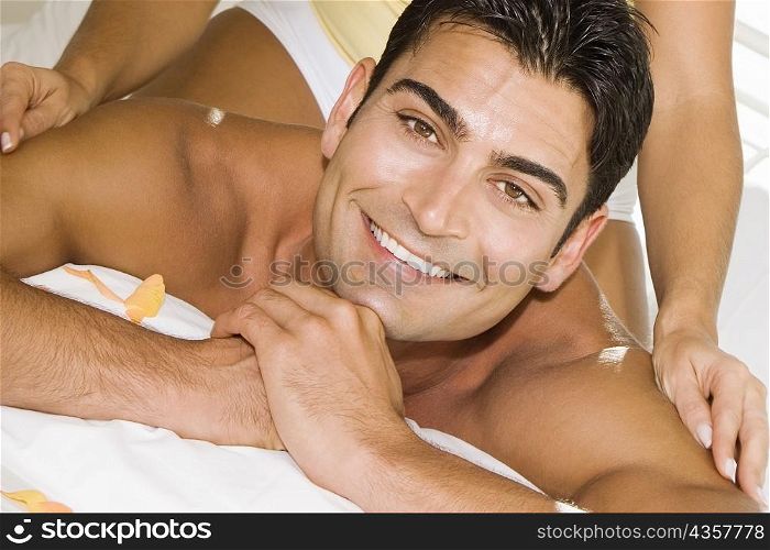 Mid adult woman massaging a mid adult man&acute;s shoulders on the bed