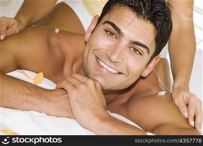 Mid adult woman massaging a mid adult man&acute;s shoulders on the bed