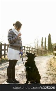 Mid adult woman obedience training her dog on rural road