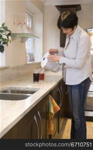 Mid adult woman pouring soda in a glass