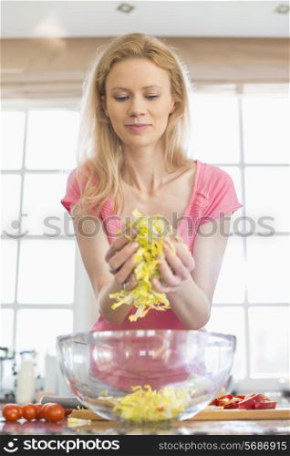 Mid adult woman preparing vegetable salad in kitchen