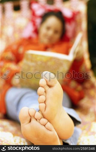 Mid adult woman reclining on the bed and looking at a photo album