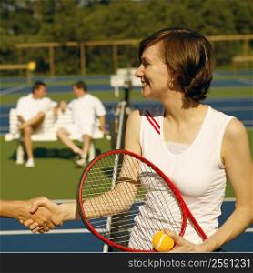 Mid adult woman shaking hands with a woman on a tennis court
