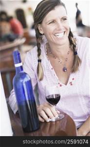 Mid adult woman sitting at a table and holding a glass of wine