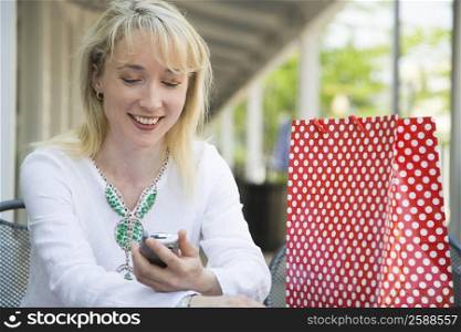 Mid adult woman sitting in a cafe and looking at a mobile phone
