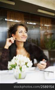 Mid adult woman sitting in a restaurant with a personal data assistant