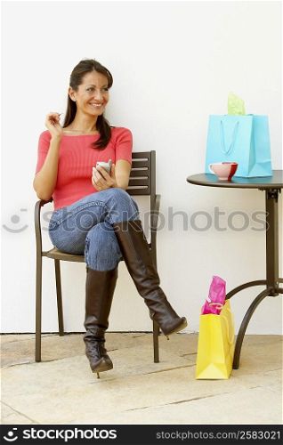 Mid adult woman sitting in an armchair and holding a personal data organizer