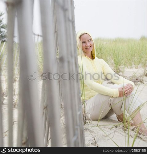 Mid adult woman sitting near a fence and smiling