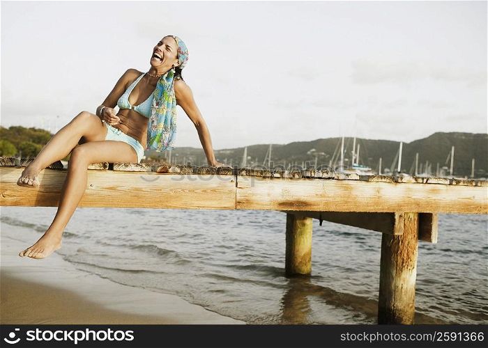 Mid adult woman sitting on a pier and smiling