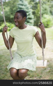 Mid adult woman sitting on a rope swing and smiling