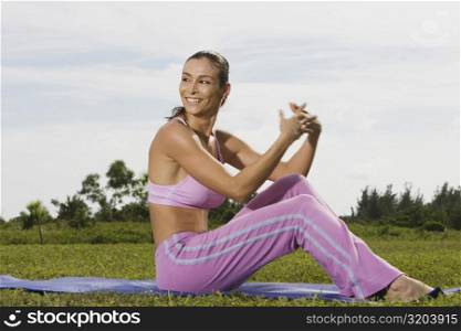 Mid adult woman sitting on an exercising mat with her hands clasped