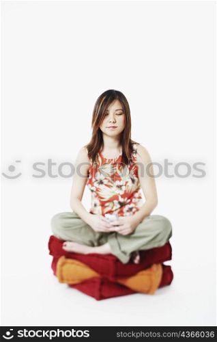 Mid adult woman sitting on cushions with her eyes closed
