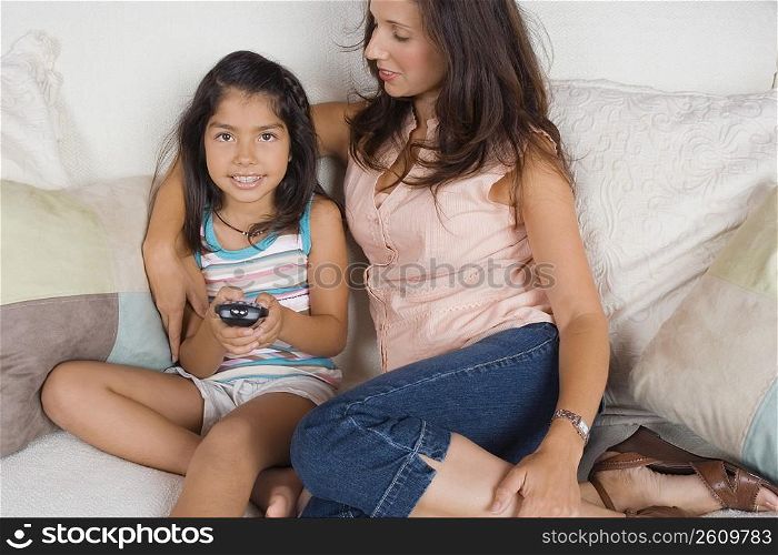 Mid adult woman sitting with her daughter on a couch