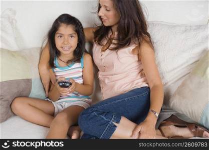Mid adult woman sitting with her daughter on a couch