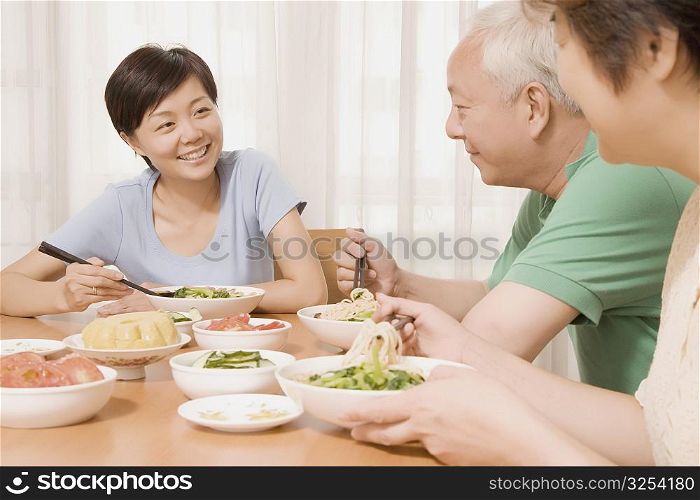 Mid adult woman sitting with her parents at a dining table