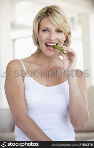 Mid Adult Woman Smiling At Camera And Eating Celery Stick