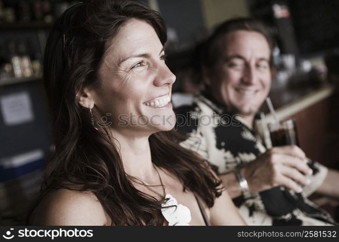 Mid adult woman smiling with a mid adult man holding a glass of drink beside her