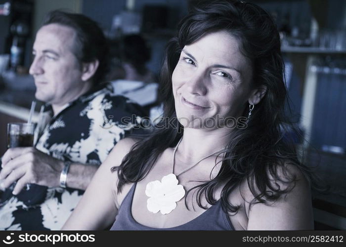 Mid adult woman smiling with a mid adult man holding a glass of drink beside her