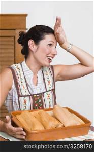 Mid adult woman smiling with a tray of breads in the kitchen