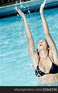 Mid adult woman splashing water in a swimming pool