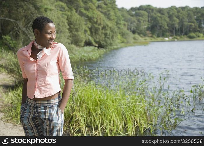 Mid adult woman standing at the lakeside and smiling