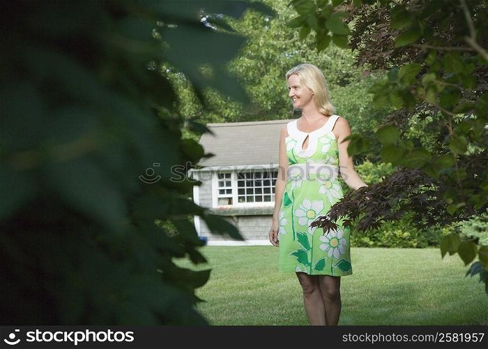Mid adult woman standing in a lawn and smiling