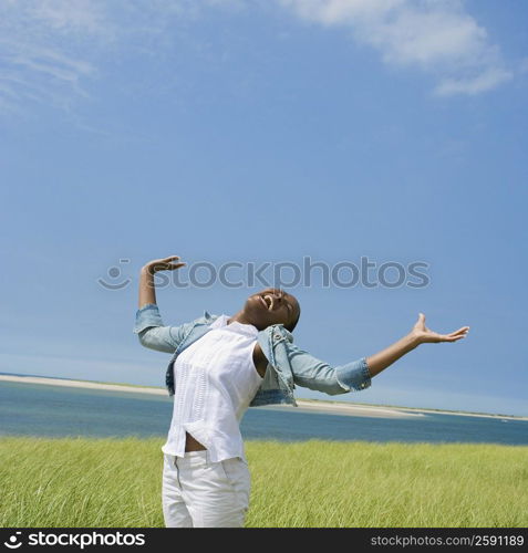 Mid adult woman standing on the beach with her arms outstretched and laughing