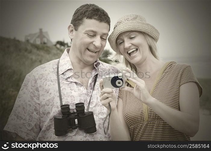 Mid adult woman standing with a mature man and holding a digital camera