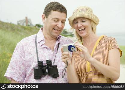 Mid adult woman standing with a mature man and holding a digital camera