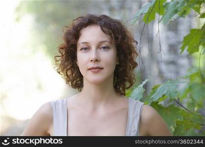 Mid adult woman stands in nature looking directly at camera