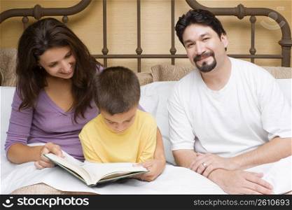 Mid adult woman teaching her son with a mid adult man sitting beside them
