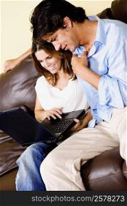 Mid adult woman using a laptop with a mid adult man sitting beside her
