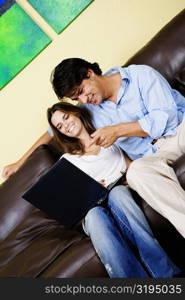 Mid adult woman using a laptop with a mid adult man sitting beside her