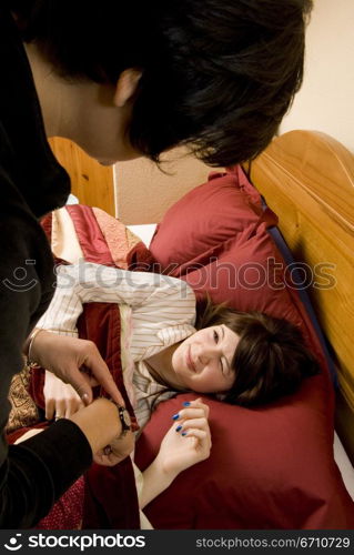 Mid adult woman waking up a her daughter lying on the bed