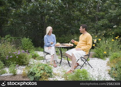 Mid adult woman with a mature man having lunch in a garden