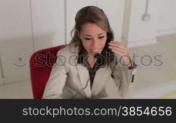 mid adult woman with headset talking on the phone and typing on keyboard. Shot using a crane