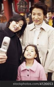 Mid adult woman with her mother and her daughter taking a photograph of themselves