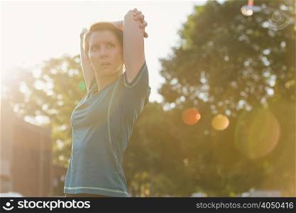 Mid adult woman, working out, stretching, outdoors