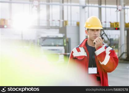Mid adult worker using walkie-talkie in shipping yard