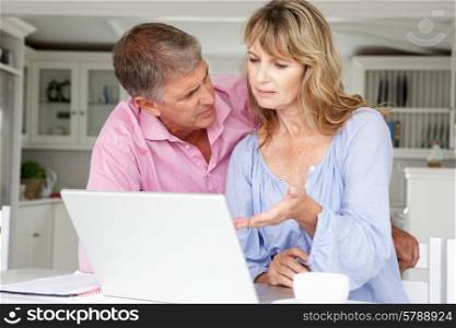 Mid age couple working at home on laptop