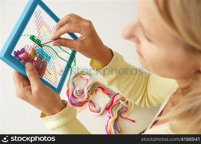 Mid age woman doing cross stitch