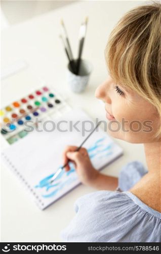Mid age woman painting with watercolors