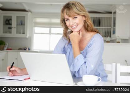 Mid age woman working at home on laptop