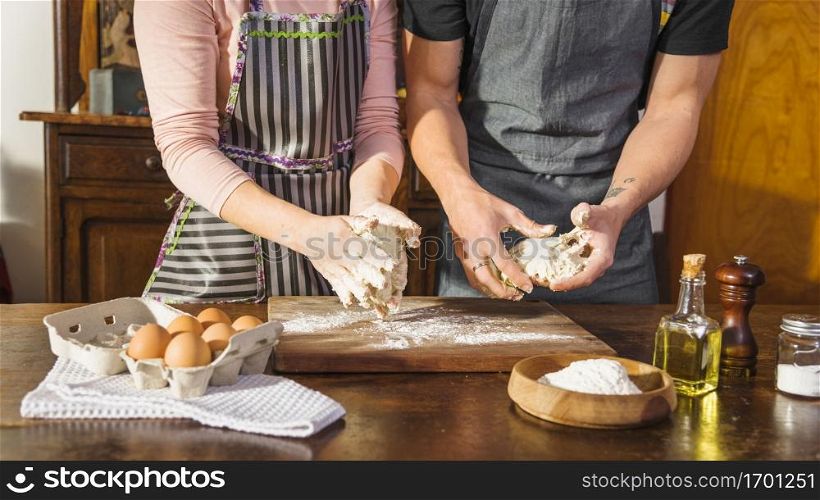 mid section couple preparing dough with baking ingredients wooden table